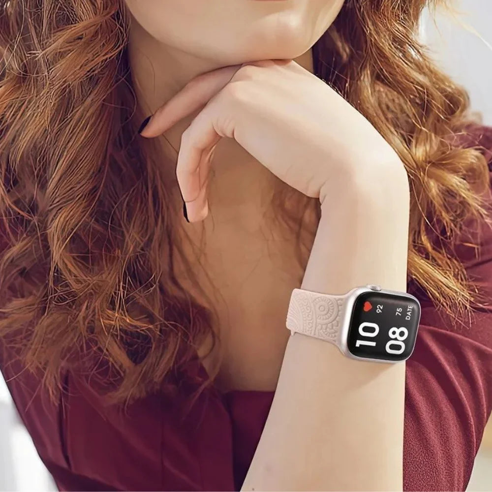 Woman wearing engraved floral silicone Apple Watch band in pink beige, displaying heart rate and time on Apple Watch face