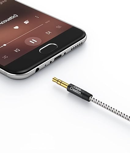3.5mm aux cable gold-plated male connector with cotton braided jacket plugged into smartphone headphone jack for music streaming
