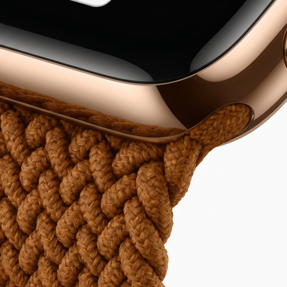 Rear view of an Apple Watch with gold case and brown braided solo loop band, showing the heart rate sensor and band connection points