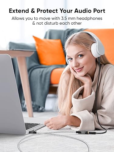 3.5mm headphone aux extension cable extending and protecting audio port allowing woman to move freely with over-ear headphones connected to laptop