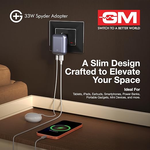 A 33W Spyder Adapter by GM shown plugged into a wall outlet, with a smartphone charging on a wooden table below. The ad includes product text, the GM logo, and a clean interior setting.