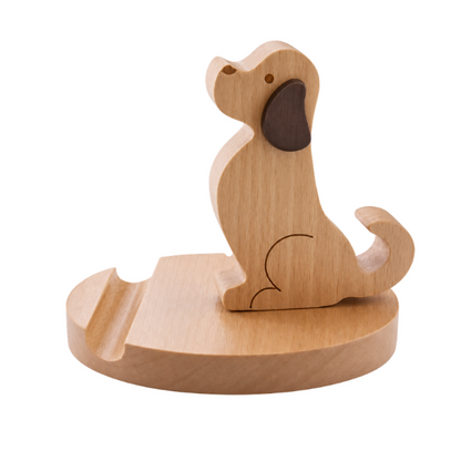 A small wooden dog-shaped object on a round wooden base, photographed on a clean white background. The dog appears to be a stylized cutout or decorative figure with a darker brown ear and engraved line details.