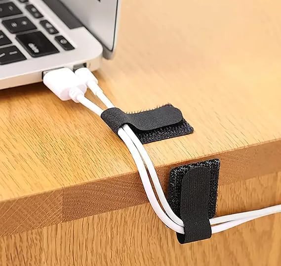 Cable management strap holding a laptop cable on a wooden desk
