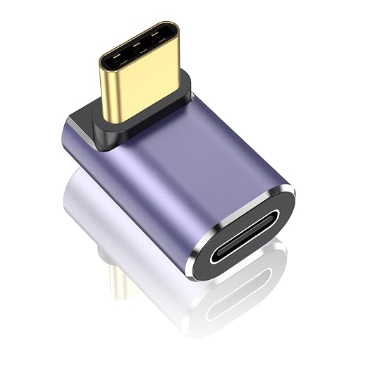 A USB-C to USB-C adapter with a metallic purple body, black end caps, and a gold-toned USB-C connector, shown on a clean white background with a soft reflection below.