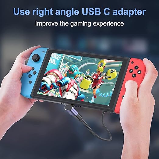 A person holds a Nintendo Switch-style console with a blue left Joy-Con and red right Joy-Con in both hands, connected to a USB-C adapter. Blue text at the top reads, 'Use right angle USB C adapter' and smaller text says, 'Improve the gaming experience.