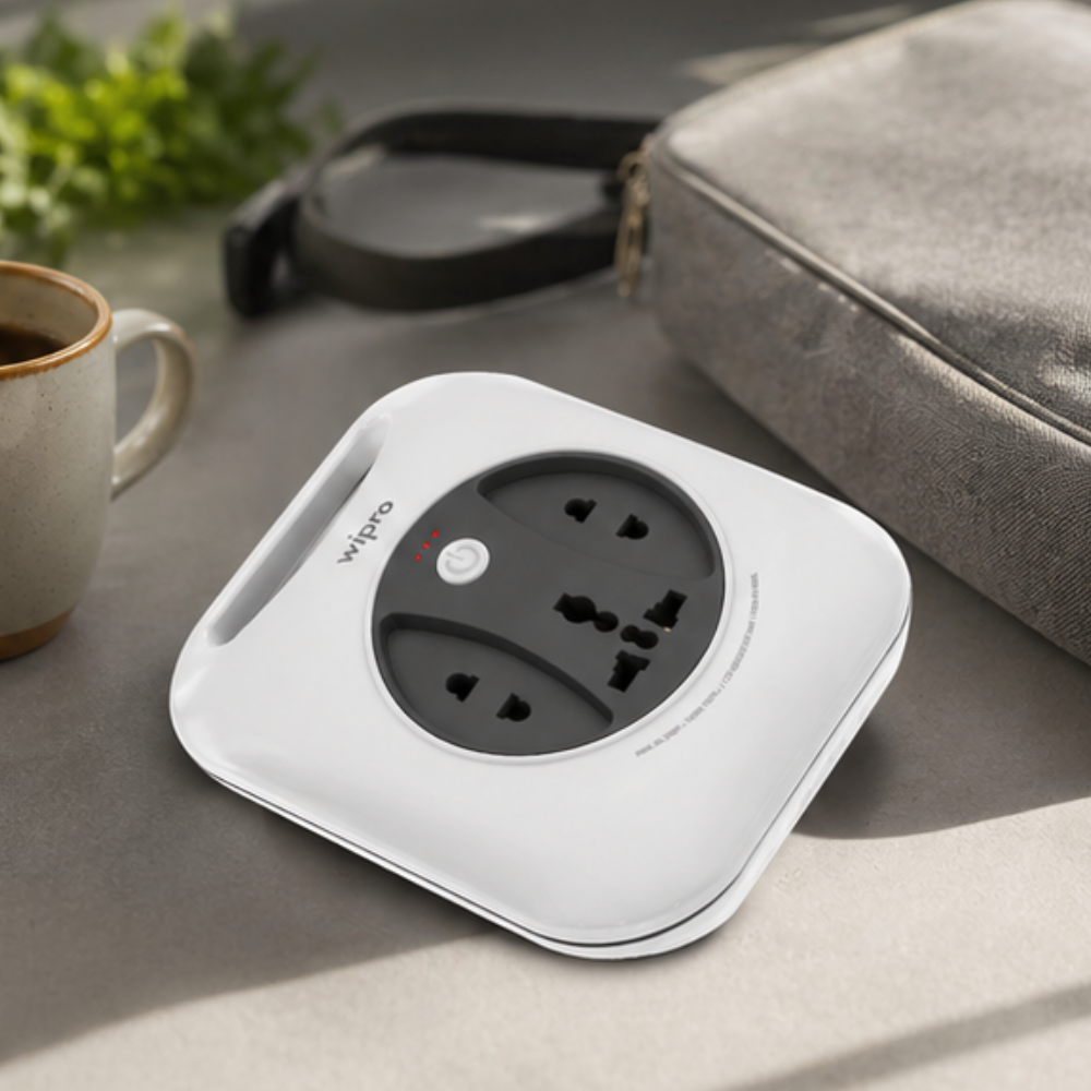 Wipro Flex Box compact 4-socket extension cord lying flat on table next to travel bag and coffee cup